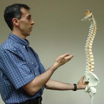 Dr. Gus demonstrating spinal anatomy with a model